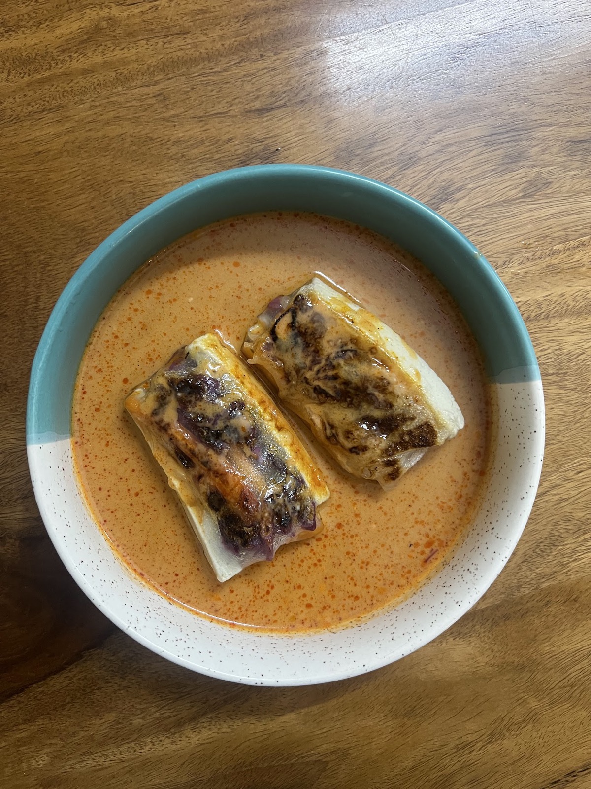 Stuffed keema rolls simmered in a rich makhani sauce in a teal bowl